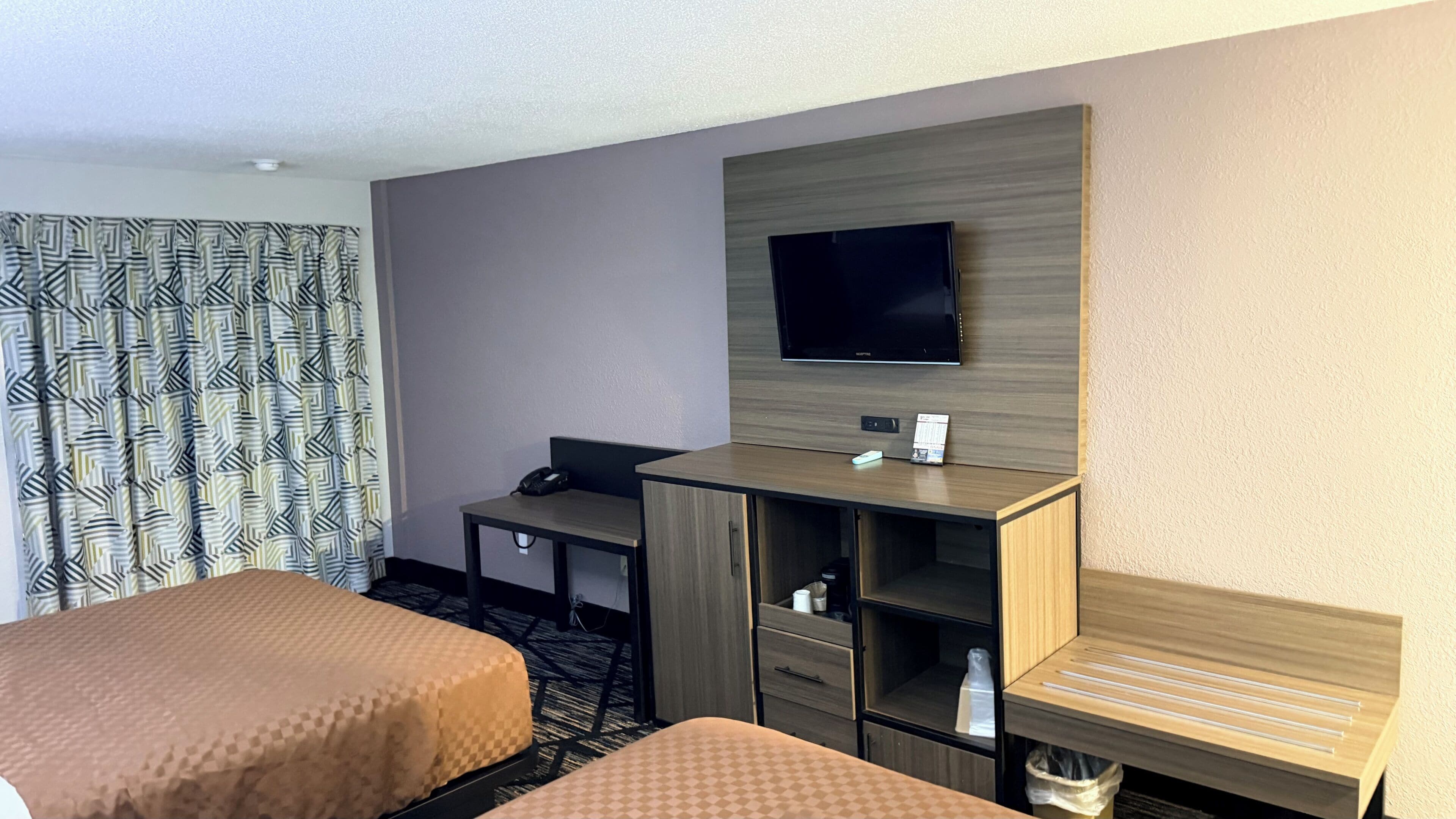 Ein Hotelzimmer mit zwei Betten, einem Schreibtisch, einem Stuhl, einem Fernseher und einer Minibar.
