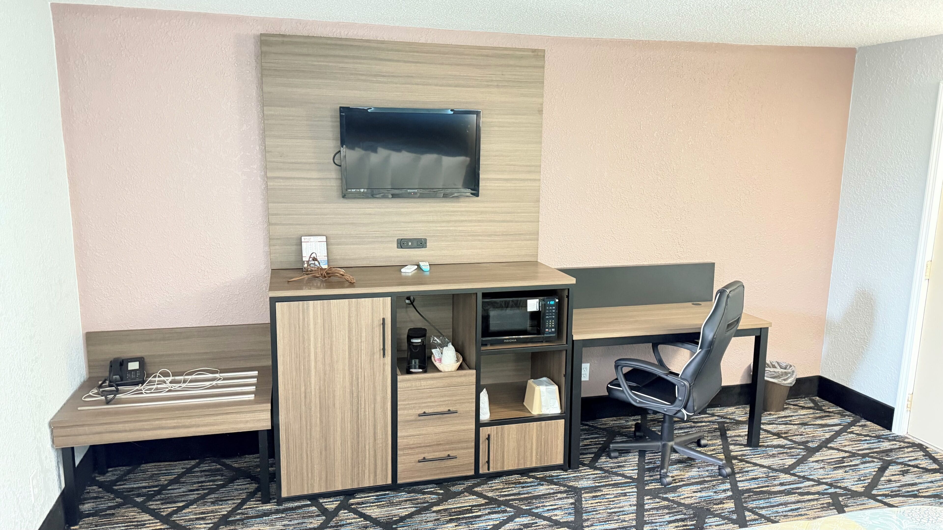 Una habitación de hotel con escritorio, silla, televisión y microondas.