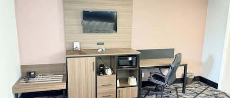 Una habitación de hotel con escritorio, silla, televisión y microondas.