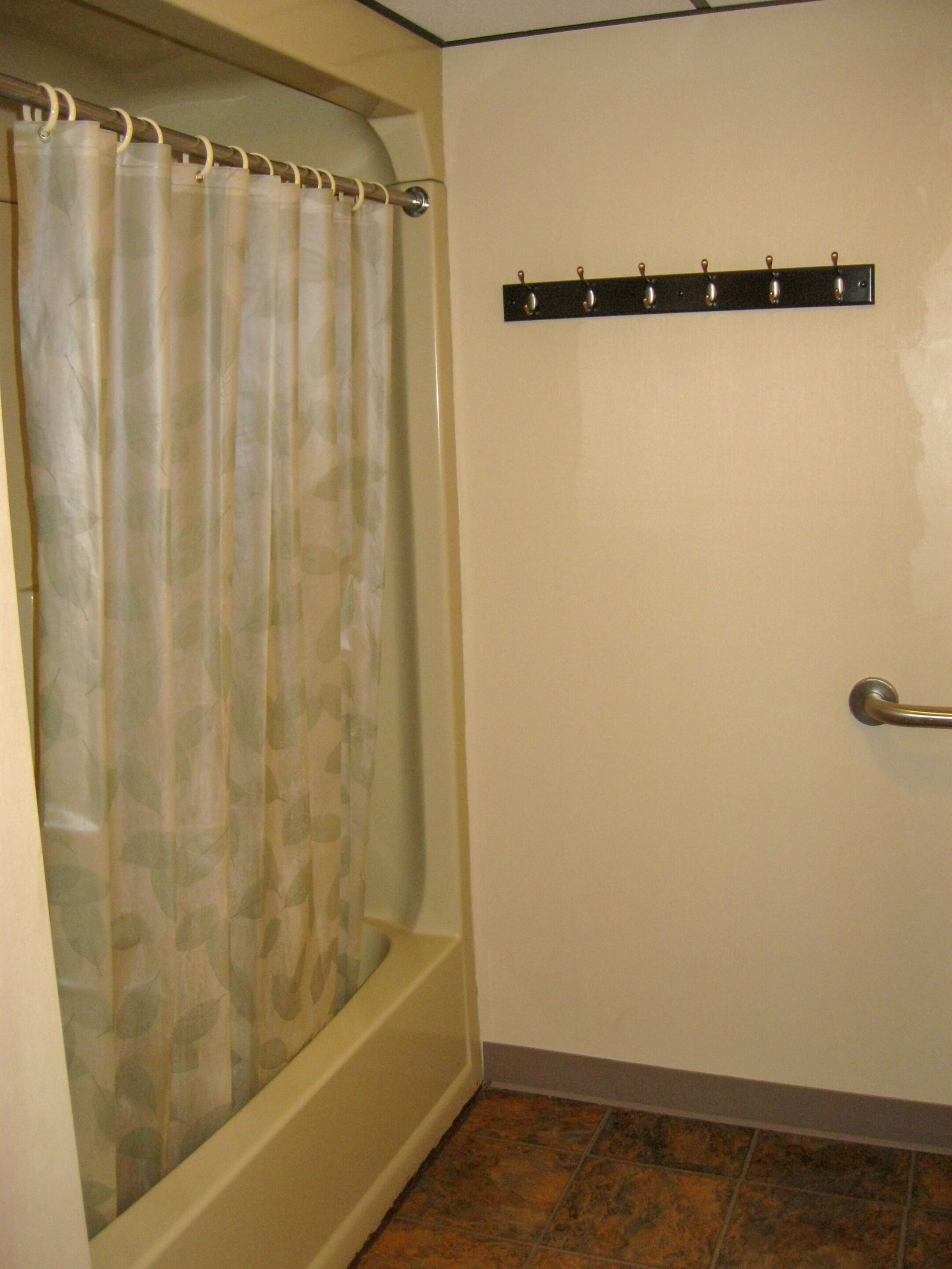 A bathroom with a shower curtain, a towel rack, and a tiled floor.