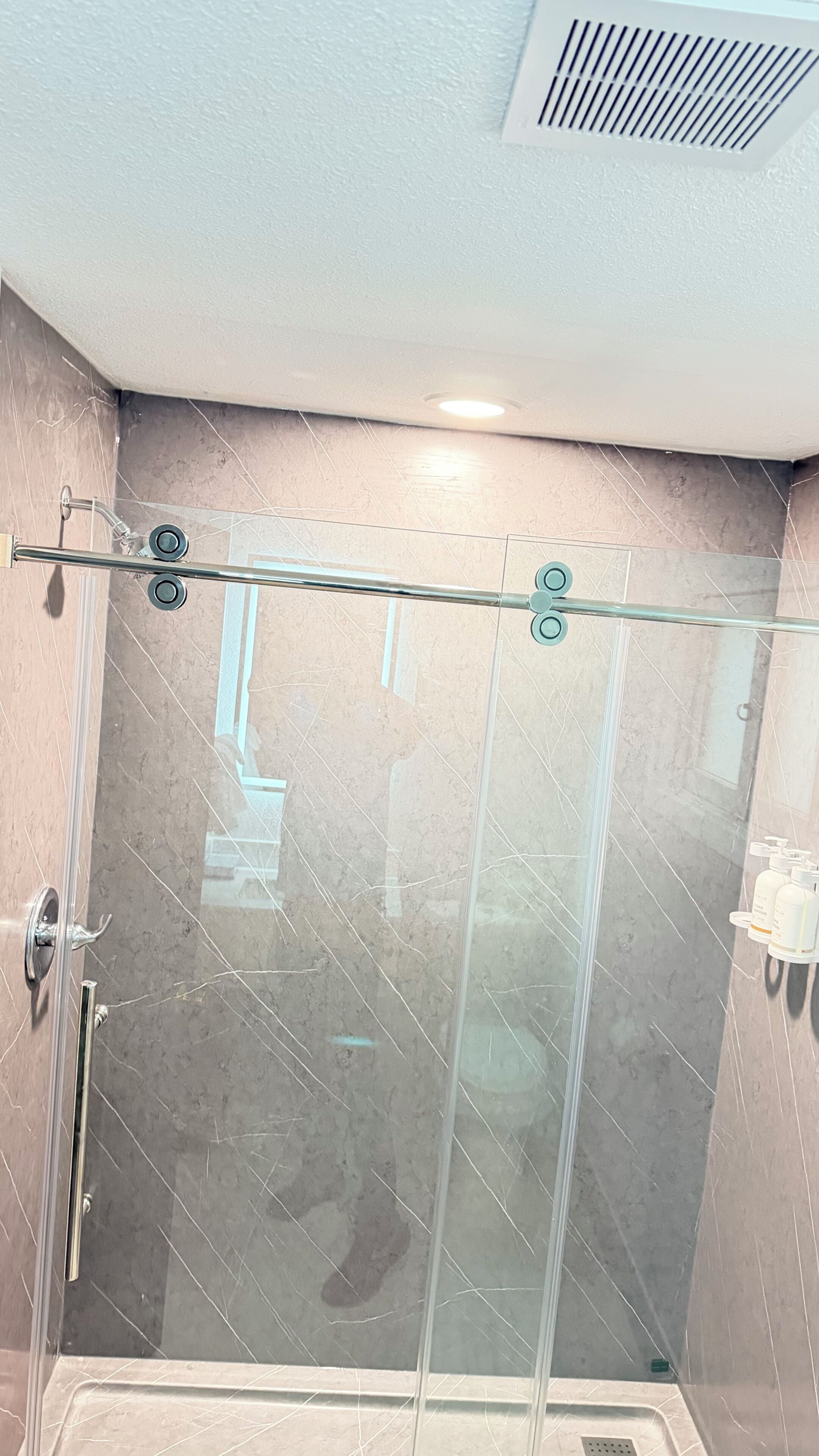 A glass-enclosed shower stall with a metal handle and a glass door.