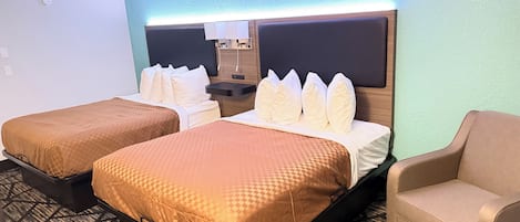 A hotel room with two beds, a small desk, a chair, and a mirror.