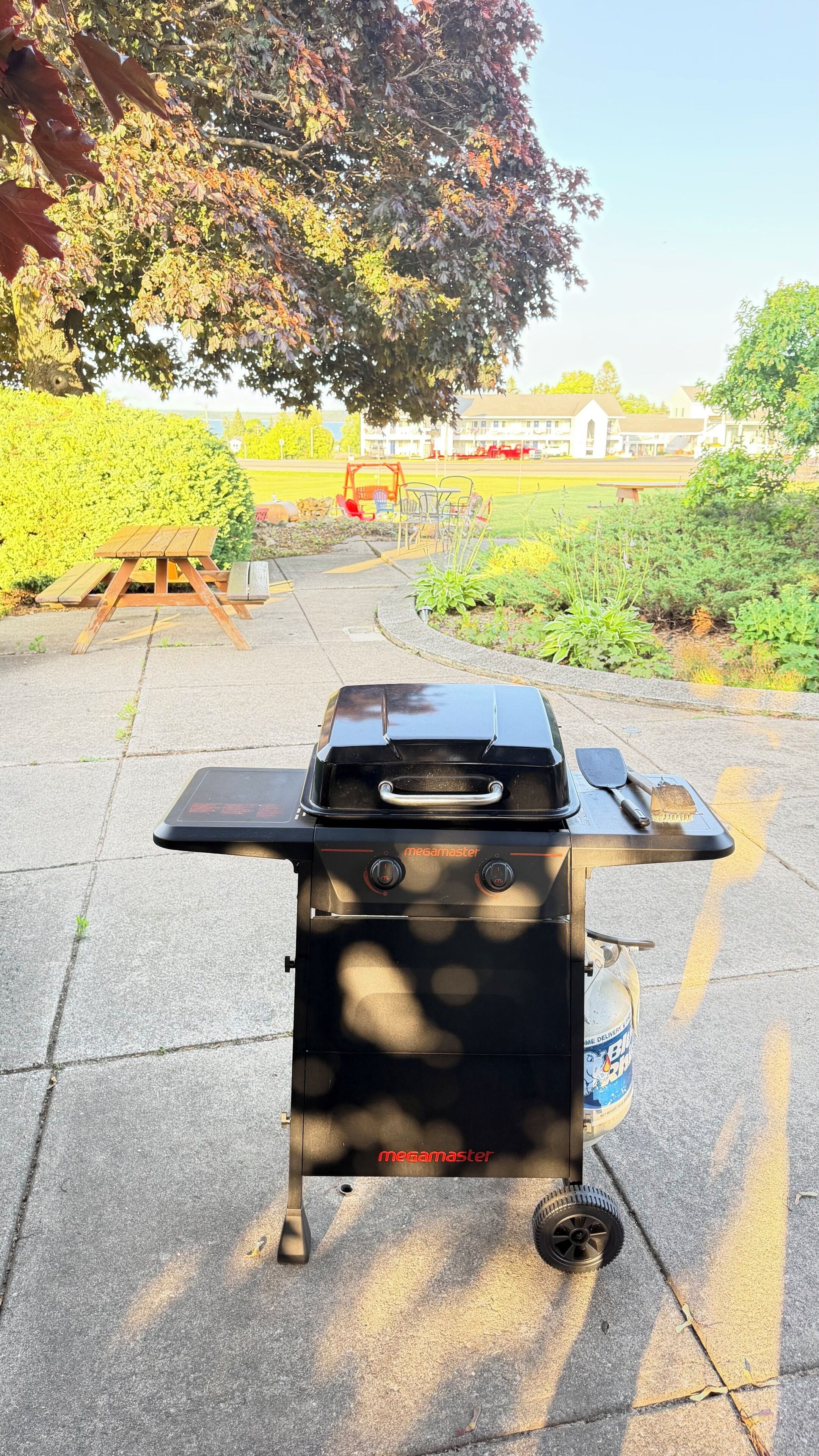 Una parrilla portátil para barbacoa con un panel de control y un depósito de agua sobre una superficie pavimentada.