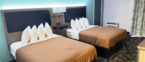 Ein Hotelzimmer mit zwei Betten, einem Schreibtisch, einem Sessel, einem Nachttisch, einer Lampe und einer Tür.