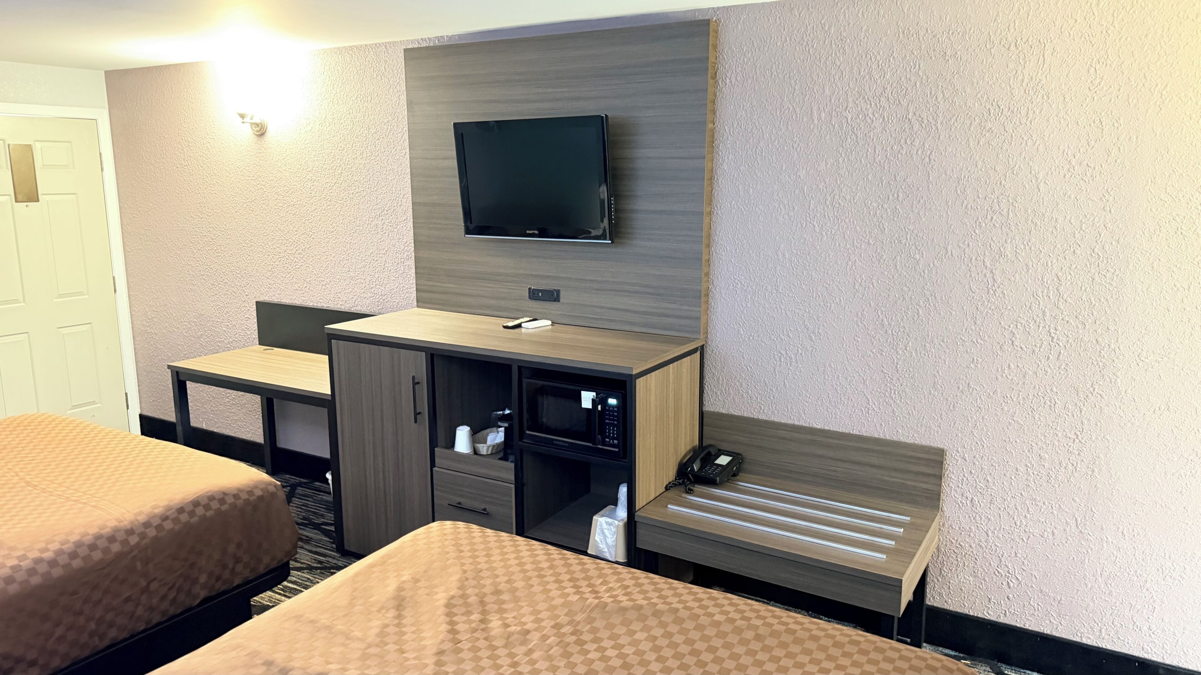 Une chambre d’hôtel avec deux lits, un bureau, une télévision, un four à micro-ondes et un téléphone.