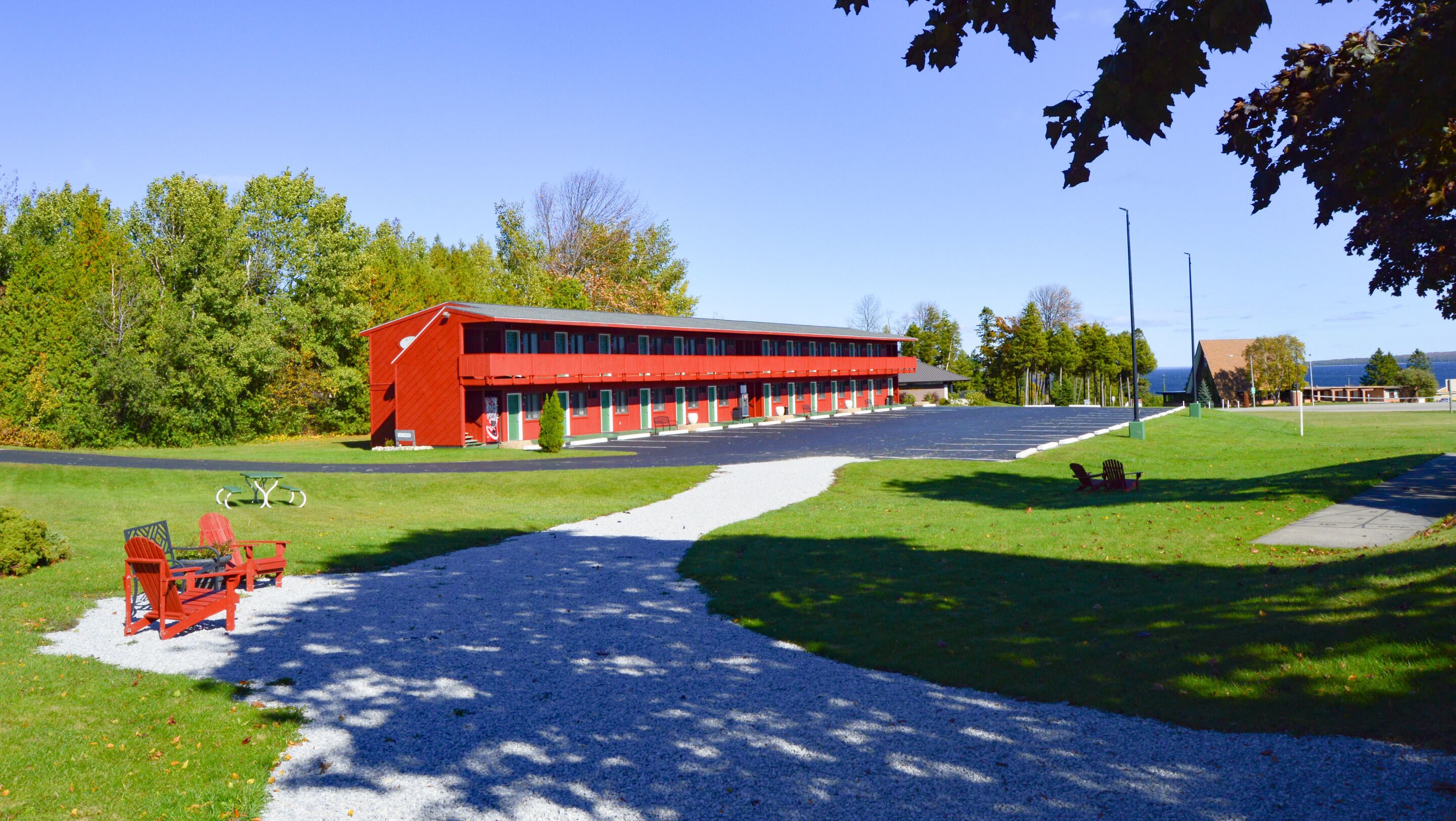 A red building with a parking lot and green lawn.