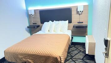 Une chambre d’hôtel comprenant un lit, des tables de chevet, une petite table et un luminaire fixé au mur.