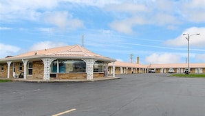 A motel with a central covered area and multiple rooms in the background. - Highway Inn (Paris)