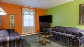 A living room with two striped sofas, a television, and a table. - Highway Inn (Paris)