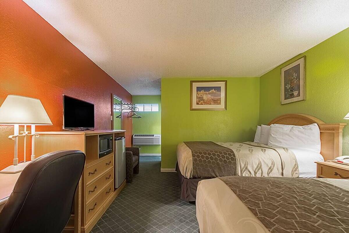 Une chambre d’hôtel équipée d’un lit, d’un bureau, d’une chaise, d’une télévision et d’une petite kitchenette.