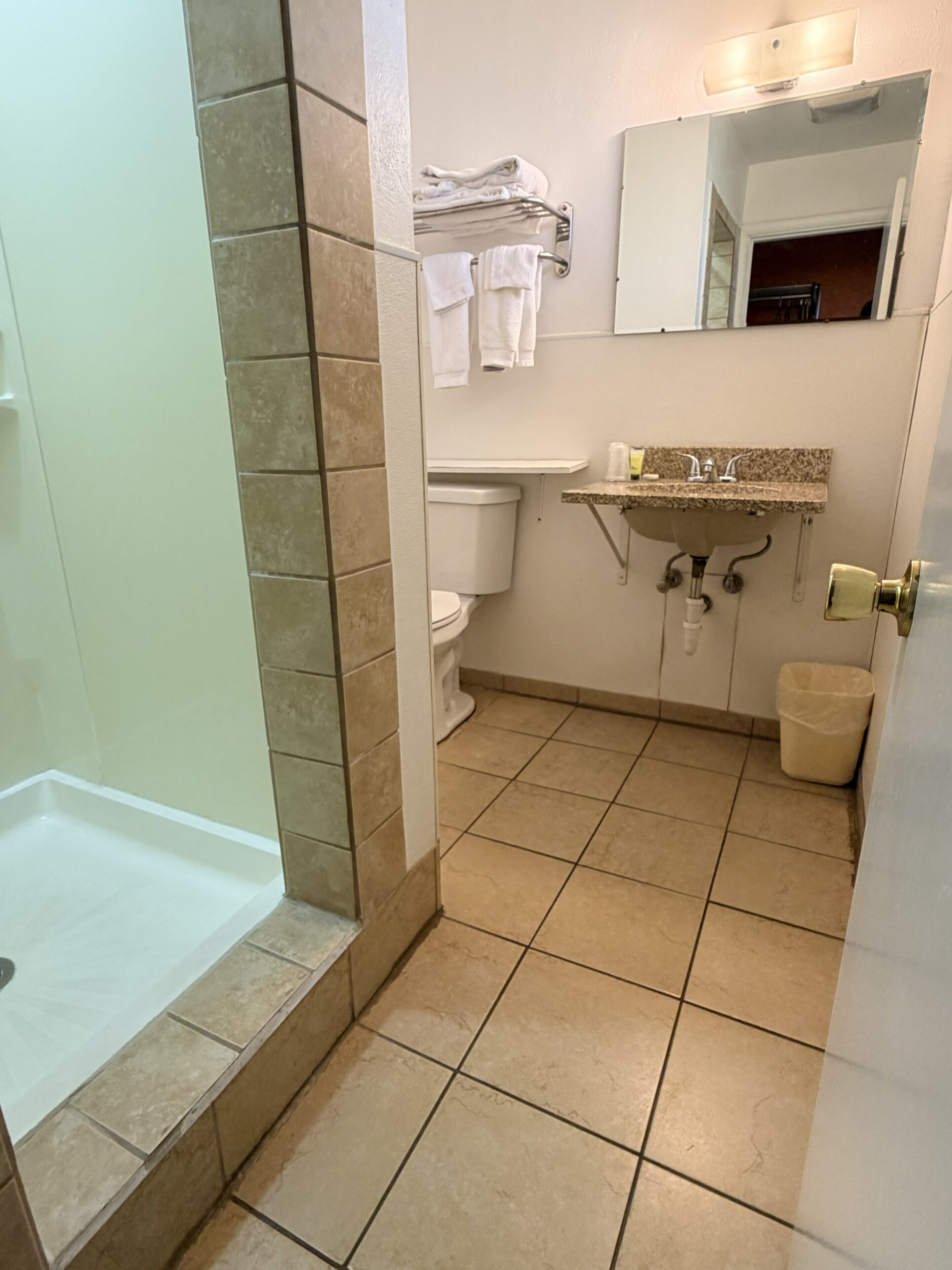 Un bagno con doccia, WC, lavandino e porta asciugamani.