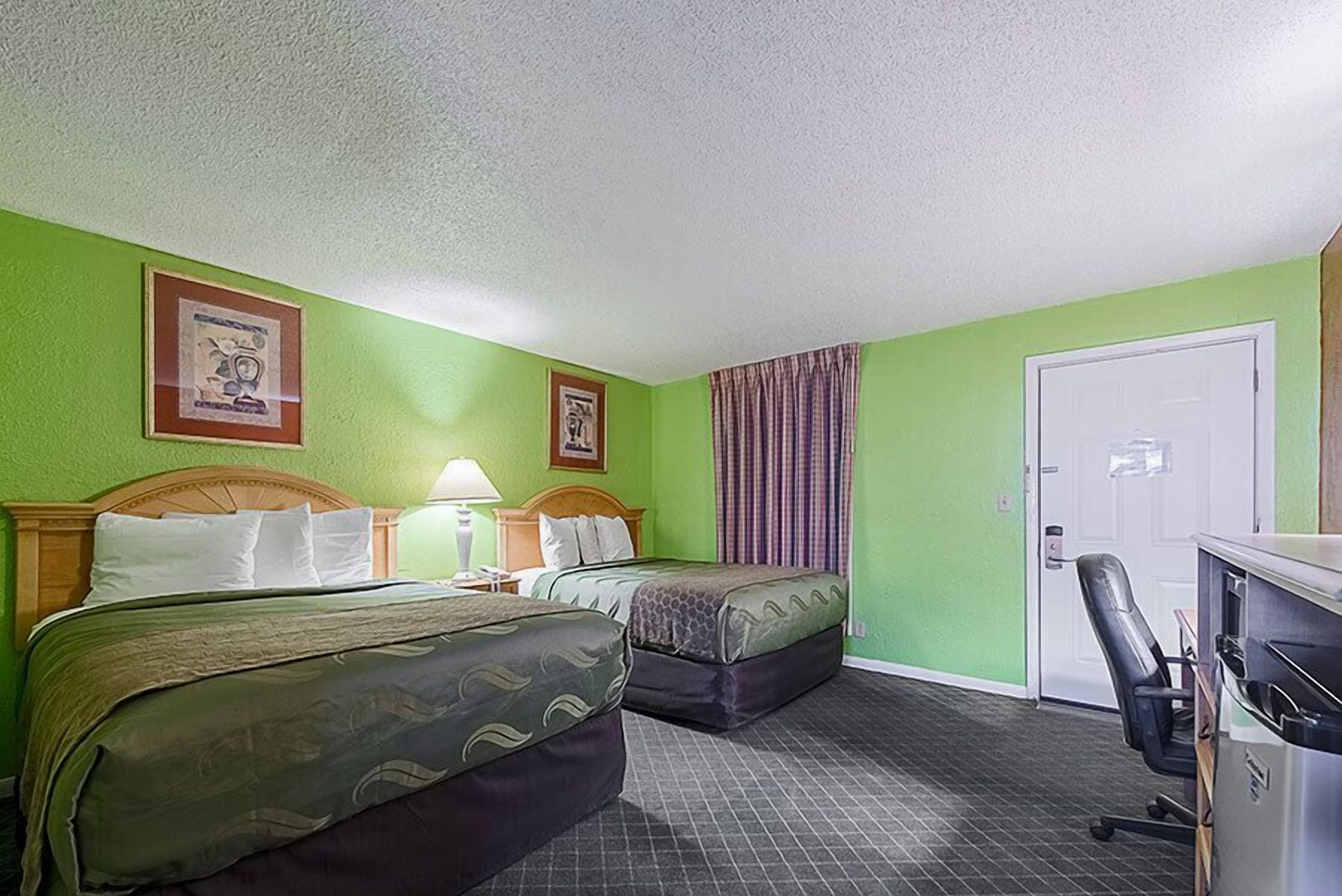 A hotel room with two beds, a desk, and a chair.