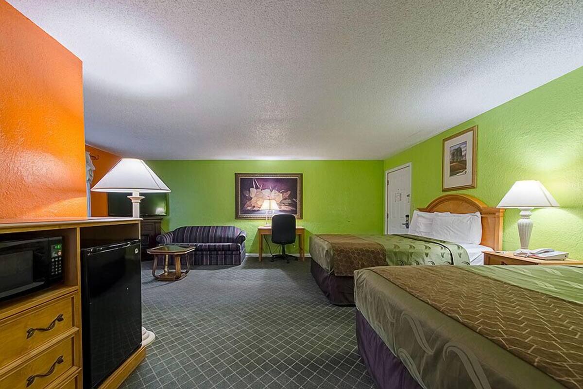 Une chambre d’hôtel avec deux lits, un bureau, une chaise, un four à micro-ondes et un téléviseur.