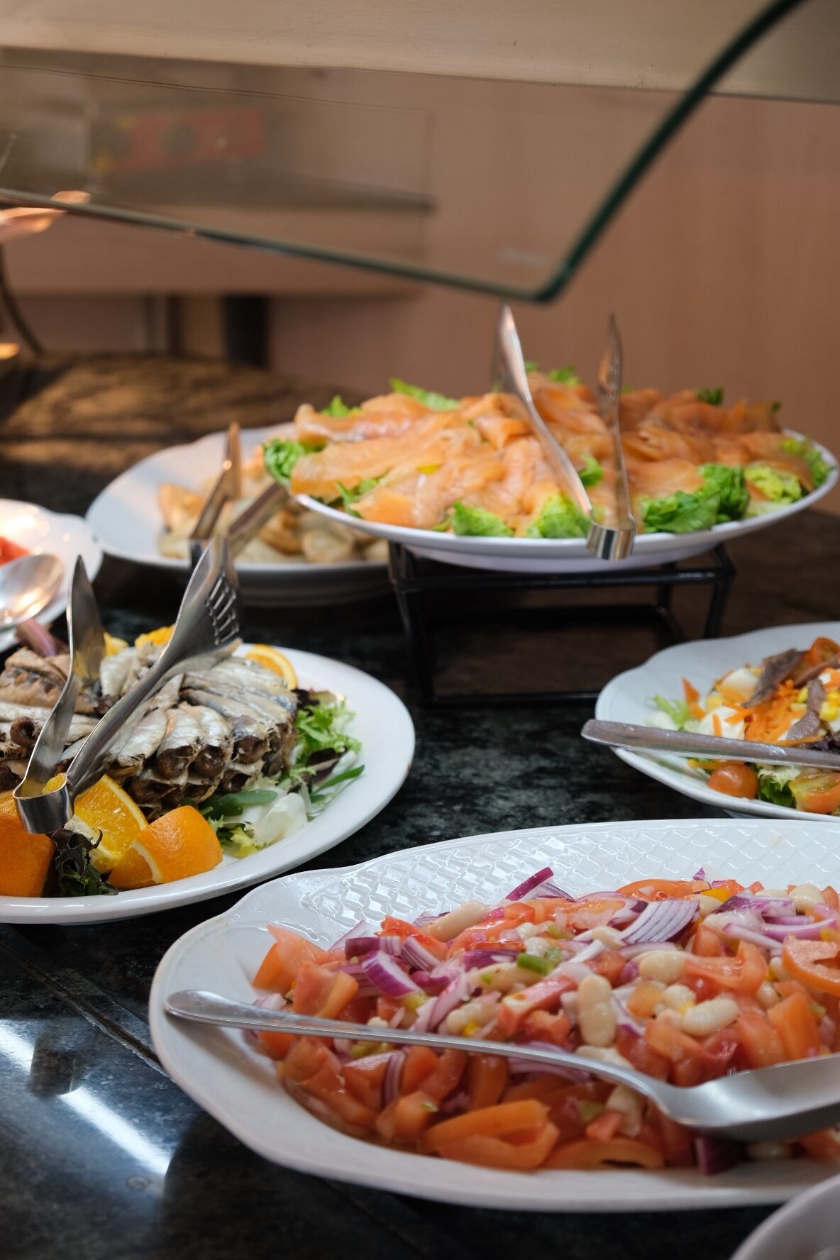 A buffet with various dishes including fish, salads, and vegetables.
