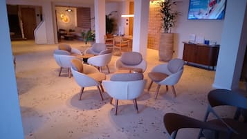 Een hotel lobby met een zithoek, een receptiebalie en een televisiescherm.