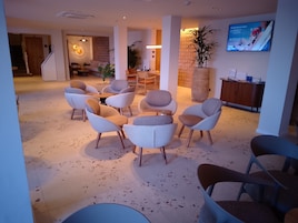 Un vestíbulo de hotel con zona de estar, un mostrador de recepción y una pantalla de televisión.