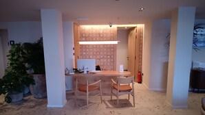 A modern dining area with a wooden table, two chairs, and a large potted plant. - Hotel Club S'illot (Manacor)