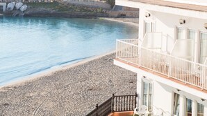 A beachfront hotel with a balcony overlooking the sea, a pebble beach, and a marina with boats. - Hotel Club S'illot (Manacor)