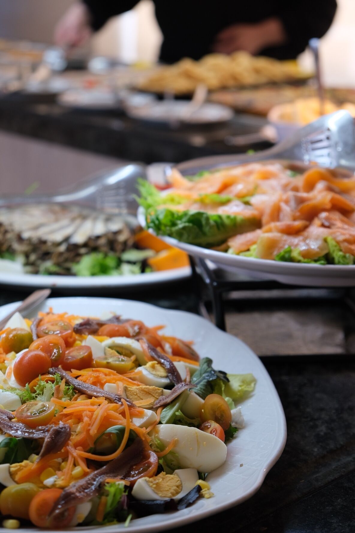 A buffet with various dishes including salads, vegetables, and meats.