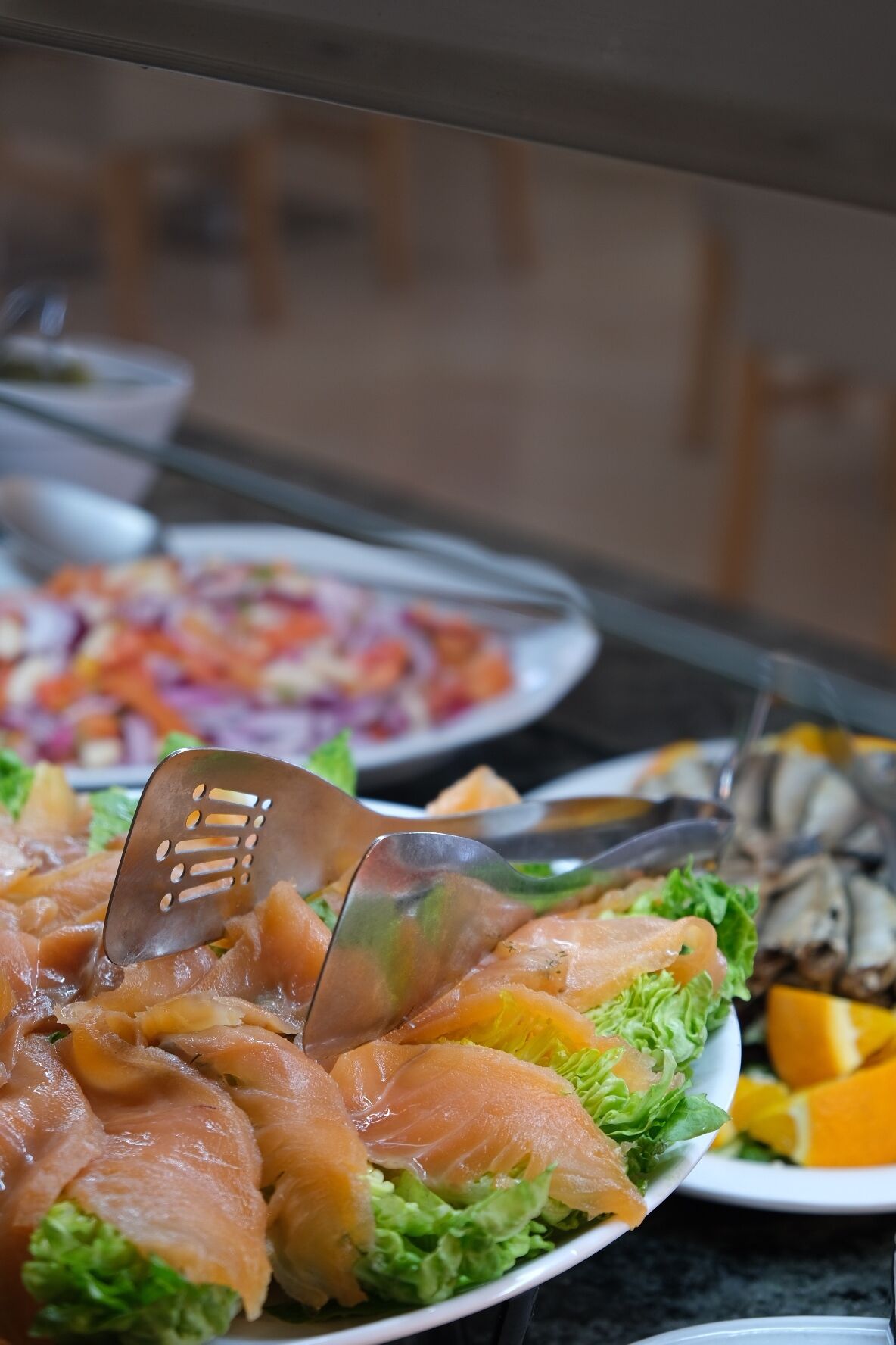 Een buffet met diverse gerechten, waaronder zalm, salade en fruit.