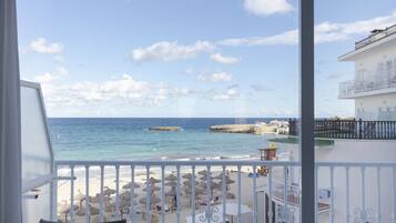 A balcony with a view of a beach, a pier, and a clear sky.