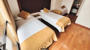 A hotel room with three single beds, each with a brown headboard and white bedding. - Hotel Dorado Ferial (Bogotá)