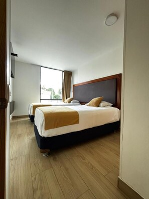A hotel room with a large bed, a smaller bed, a window, and a door. - Hotel Dorado Ferial (Bogotá)