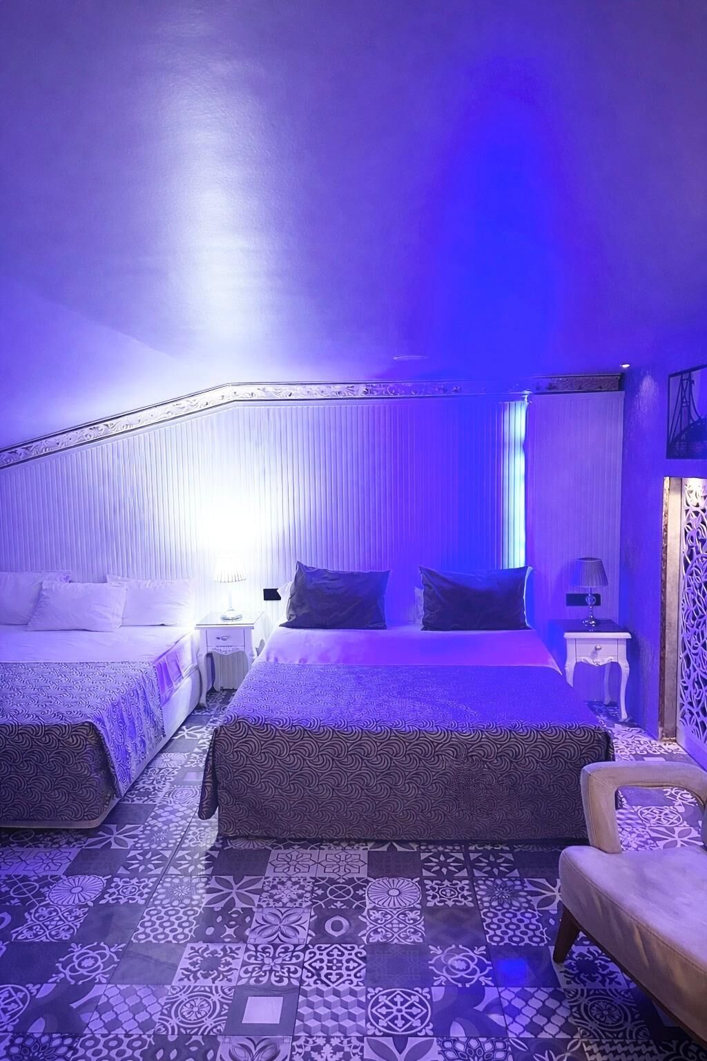 Una habitación con dos camas, una silla y suelo estampado.