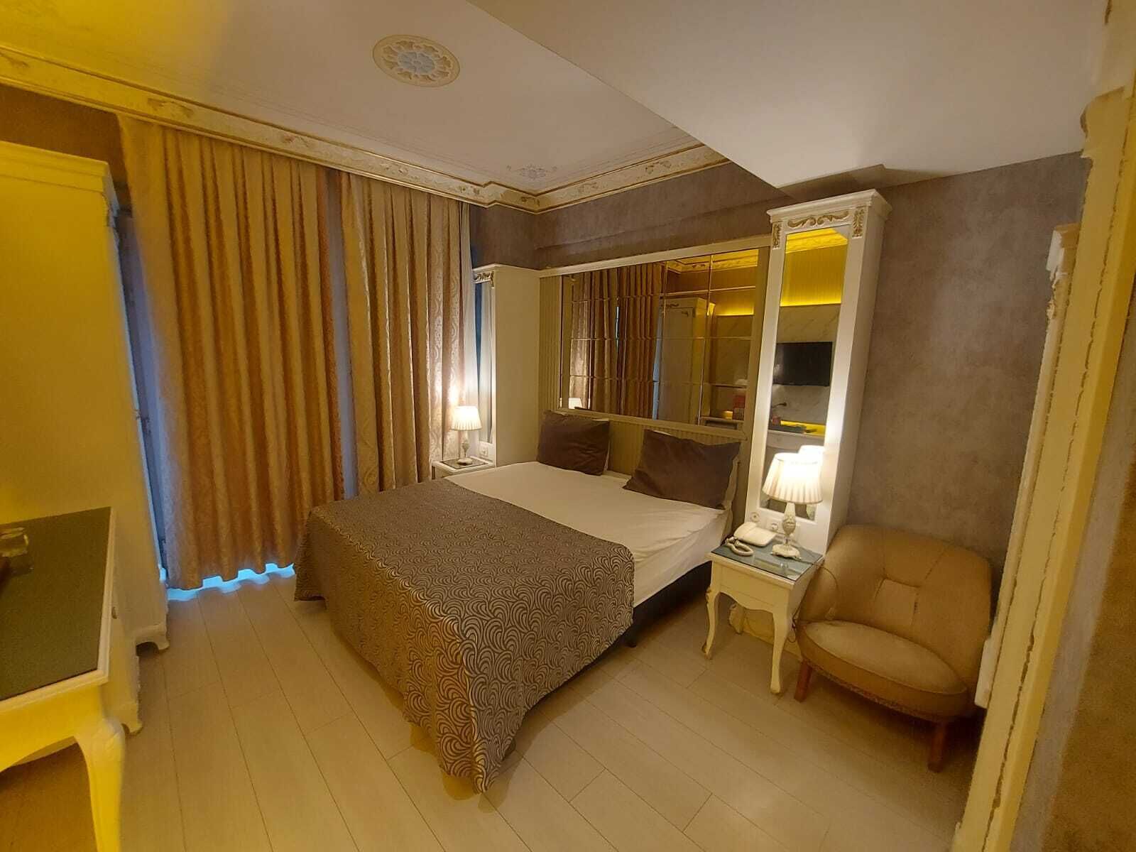 Ein Hotelzimmer mit Bett, Sessel, Schreibtisch und einem großen Spiegel.