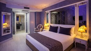 A spacious bedroom with a large bed, two bedside tables with lamps, a chair, and a mirror. - Leyenda Hotel (Istanbul)