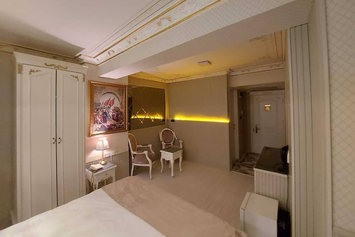 Een hotelkamer met een groot bed, een bureau, een stoel, een spiegel en een schilderij aan de muur.