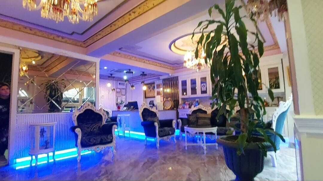 A spacious lobby with ornate chandeliers, plush seating, and a large potted plant.