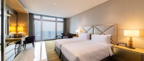 Quarto de hotel com duas camas, uma escrivaninha e uma cadeira.