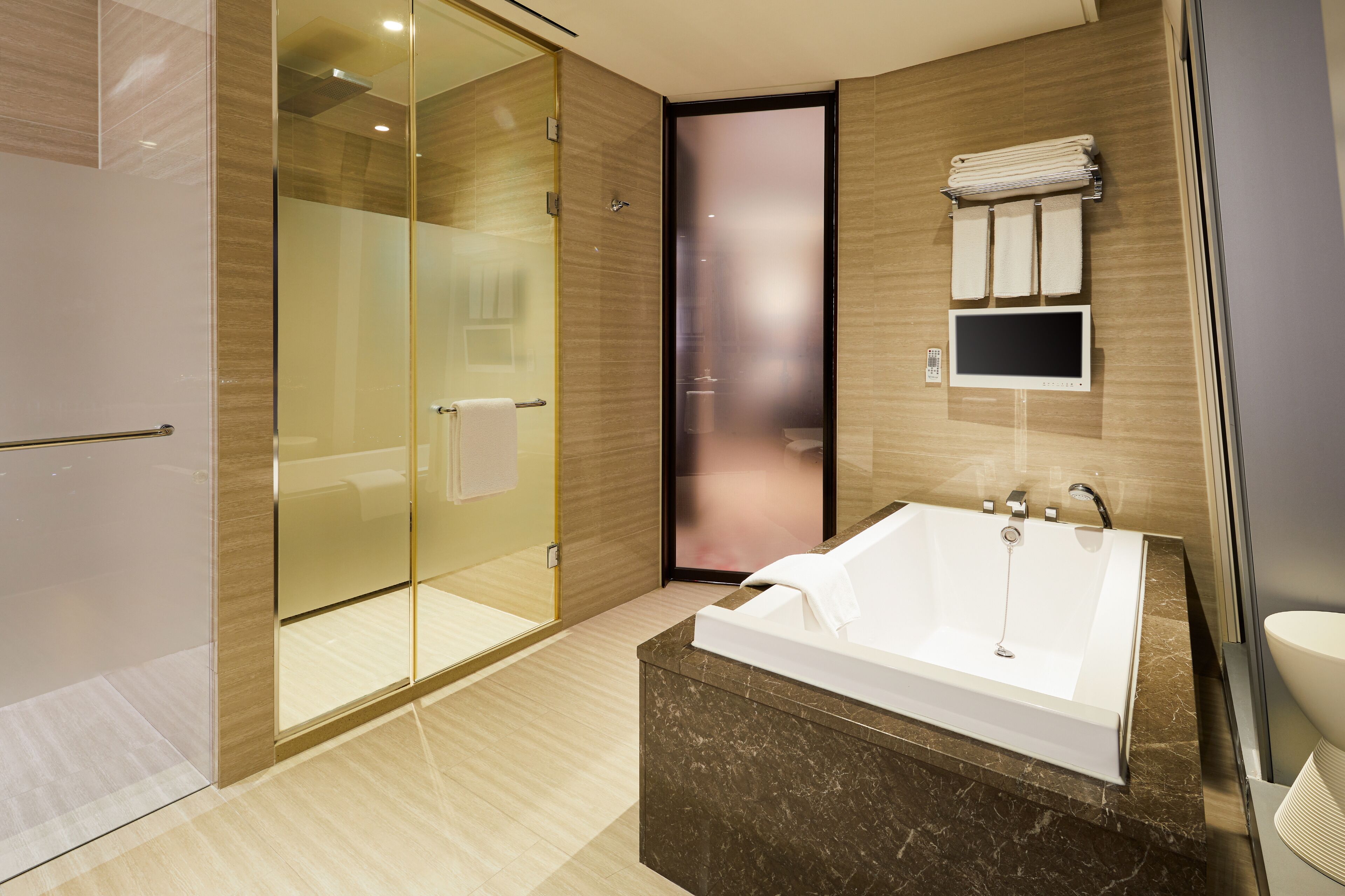 A modern bathroom with a glass shower enclosure, a large bathtub, and a vanity with a mirror.