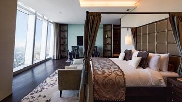 A spacious bedroom with a large bed, a sitting area, and a view of the city.