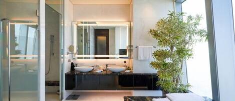 A modern bathroom with a glass shower enclosure, two sinks, a large mirror, and a bathtub.