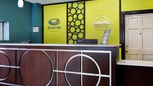 A reception desk with a wooden design and a yellow wall with circular patterns and logos. - Econo Lodge Selma - Smithfield (Selma)