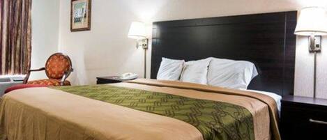 Quarto de hotel com uma cama, duas luminárias de cabeceira, mesa de cabeceira, uma cadeira e uma janela com cortinas.