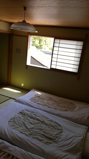 Una stanza con tatami, un paravento shoji e una lampada a sospensione.