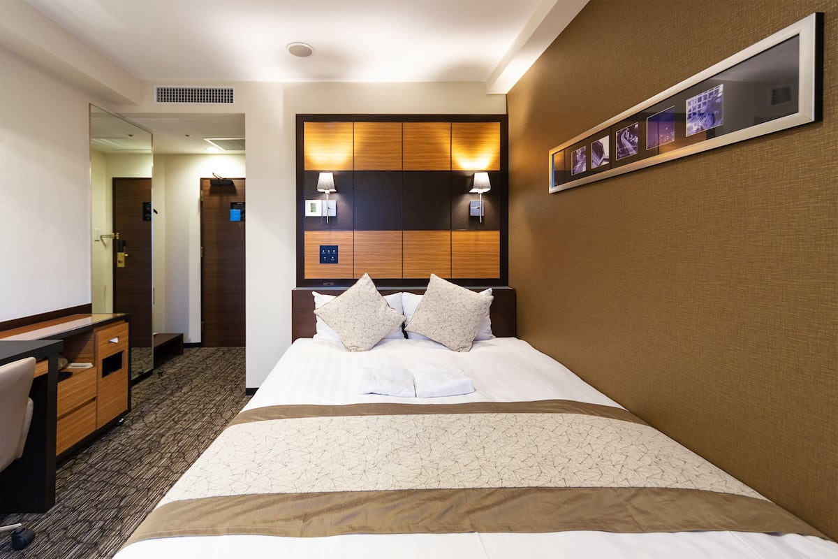 Ein Hotelzimmer mit einem großen Bett, einem Schreibtisch und einem Spiegel.