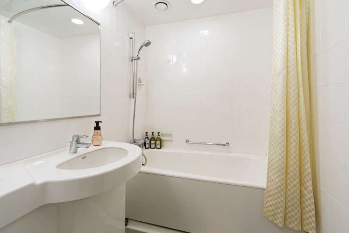 Een badkamer met een wastafel, spiegel, douche en bad.