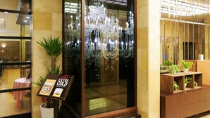 A lobby with a glass partition, a chandelier, and a reception desk with potted plants. - KOKO HOTEL Shinjuku Yotsuya (Tokyo)