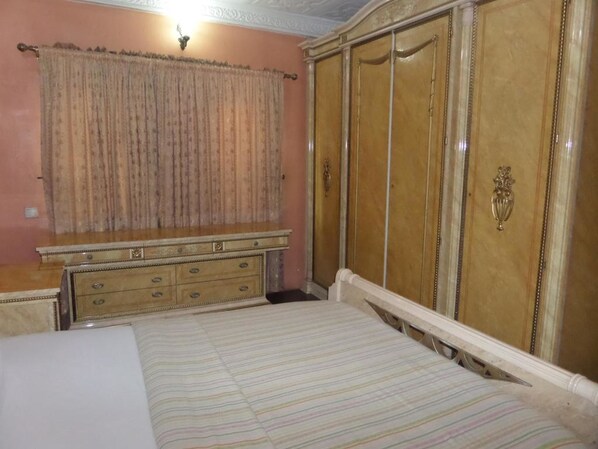 A bedroom with a bed, a dresser, and a wardrobe.