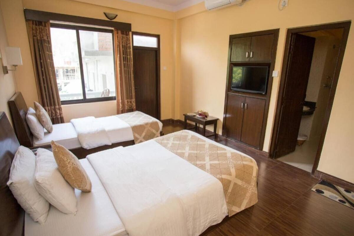 A hotel room with two beds, a TV, a small table, and a wardrobe.