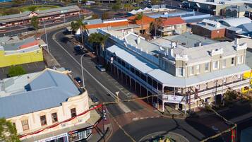 A hotel with a central courtyard, a roundabout, and a street with shops and a large building with a 'Coles' sign.