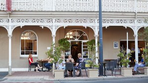 An outdoor cafe with ornate white railings, multiple seating areas, and potted plants. - Rose Hotel & Motel (Bunbury)