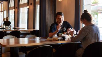 A restaurant with wooden tables and chairs, large windows, and a modern interior design.