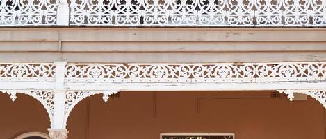 Un edificio de dos pisos con un balcón que presenta barandillas blancas ornamentadas. La planta baja tiene un letrero de restaurante.
