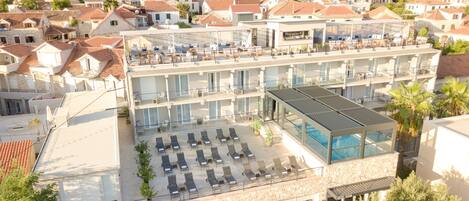 Un hotel con varios pisos, zonas de estar al aire libre y una piscina.