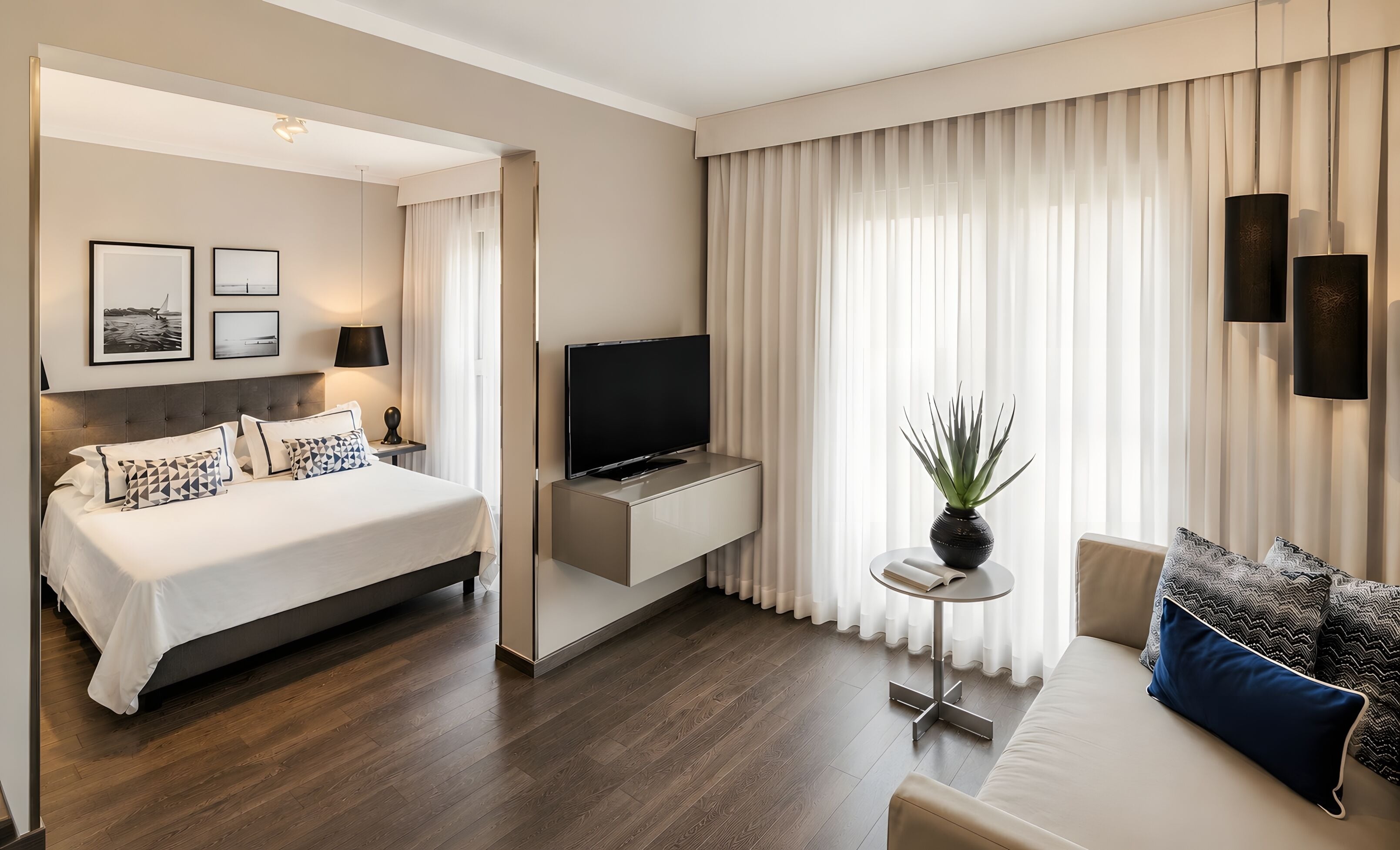 Et hotelværelse med en seng, fjernsyn, et lille bord med en plante og en sofa.